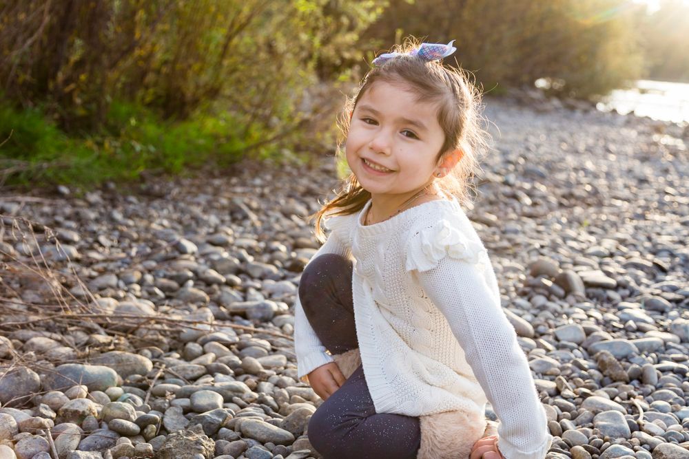 4 year old kneeling in the rocks on the river shore