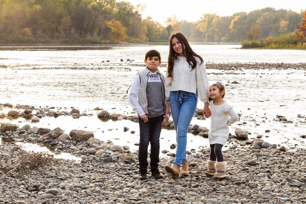 3 kids posing full length with the river winding behind them
