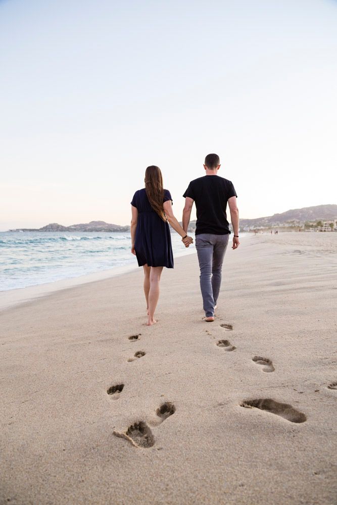couple walking on beach with footstep leading to them