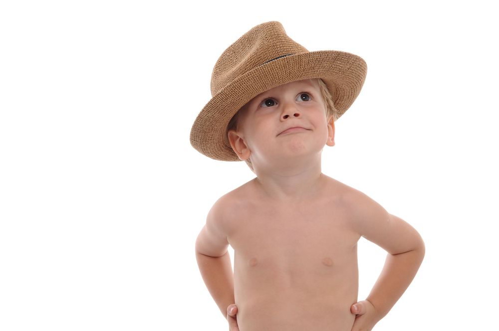 Young child wearing a brown fedora hat strikes a confident pose against white background.