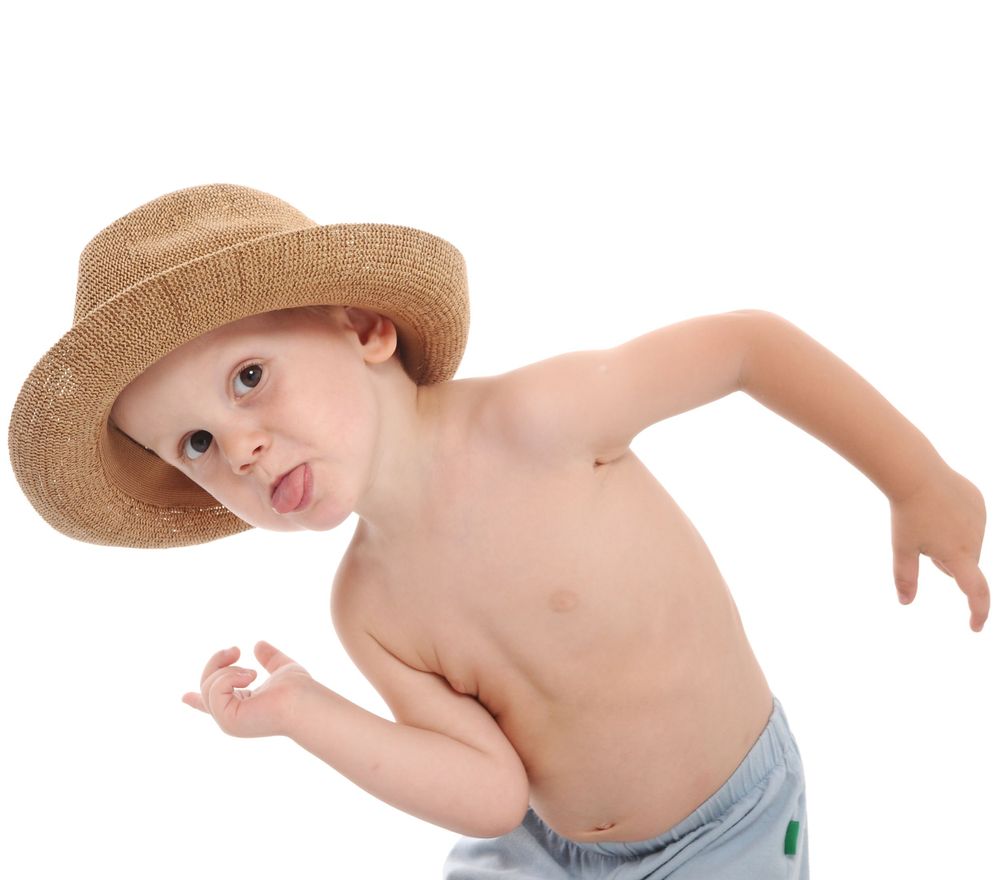 Child in straw hat leaning sideways in playful pose.