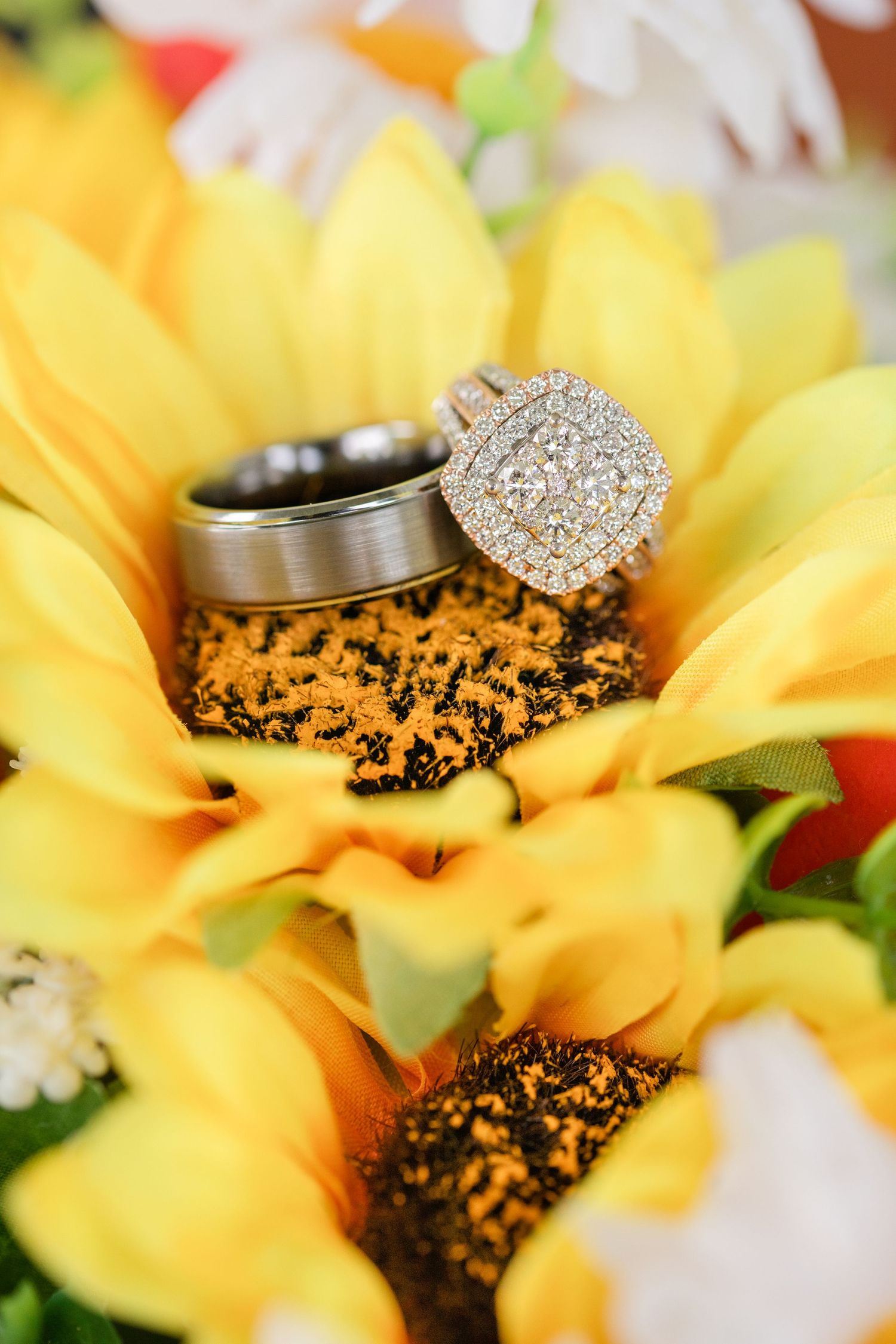 Diamond wedding rings nestled in bright yellow sunflower petals.
