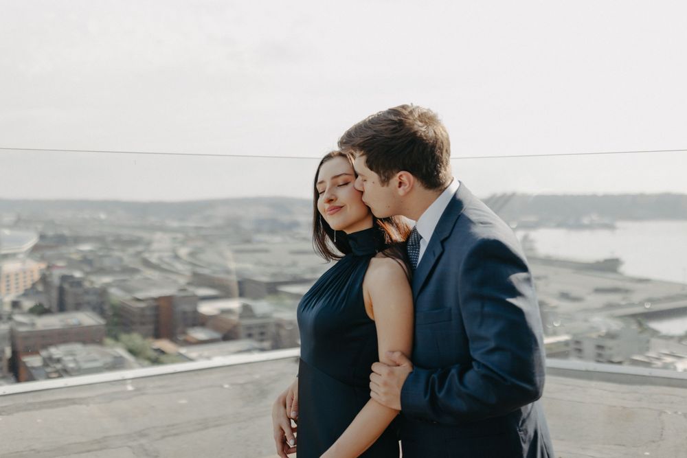 Intimate moment between couple sharing an embrace on urban rooftop with city views.