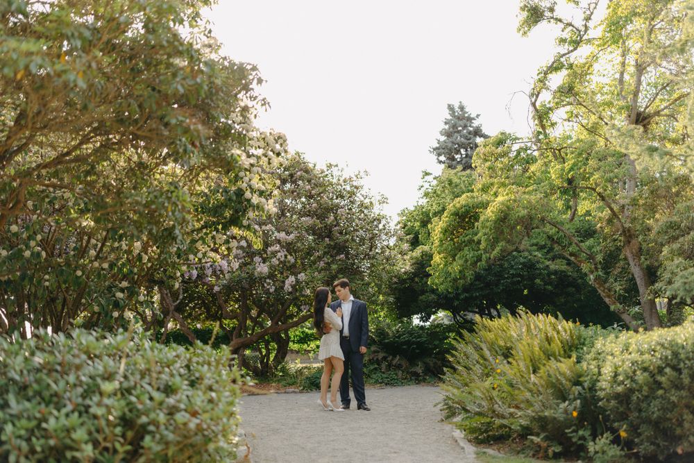An elegant couple walking together on a winding path through a verdant garden.