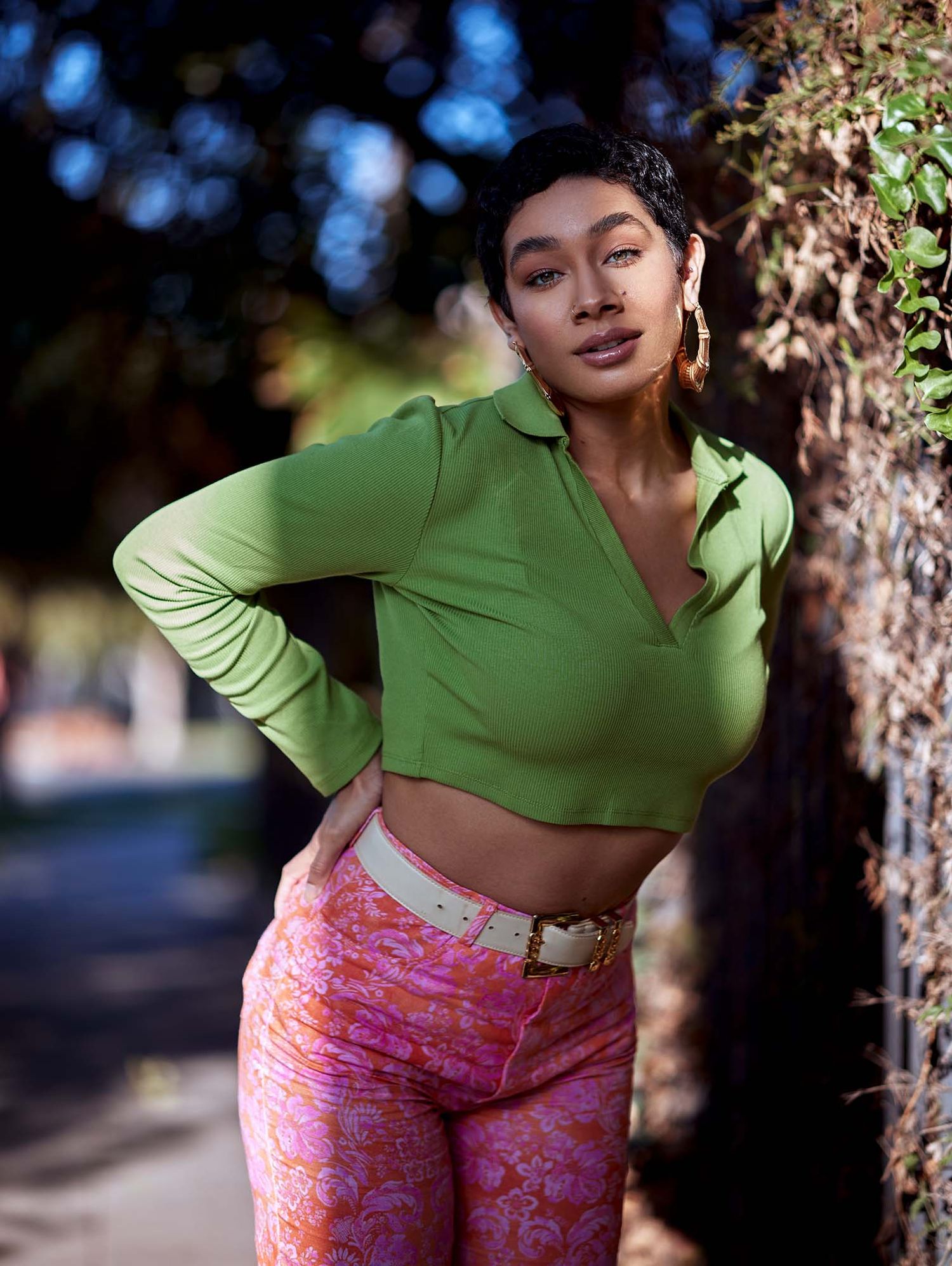 Stylish outdoor portrait featuring a green crop top and pink patterned pants.