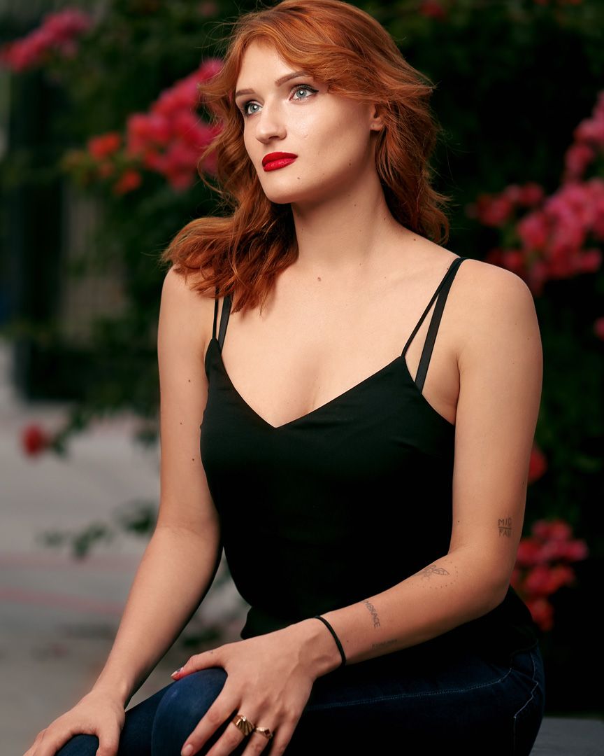 Portrait in black dress against floral background during golden hour.
