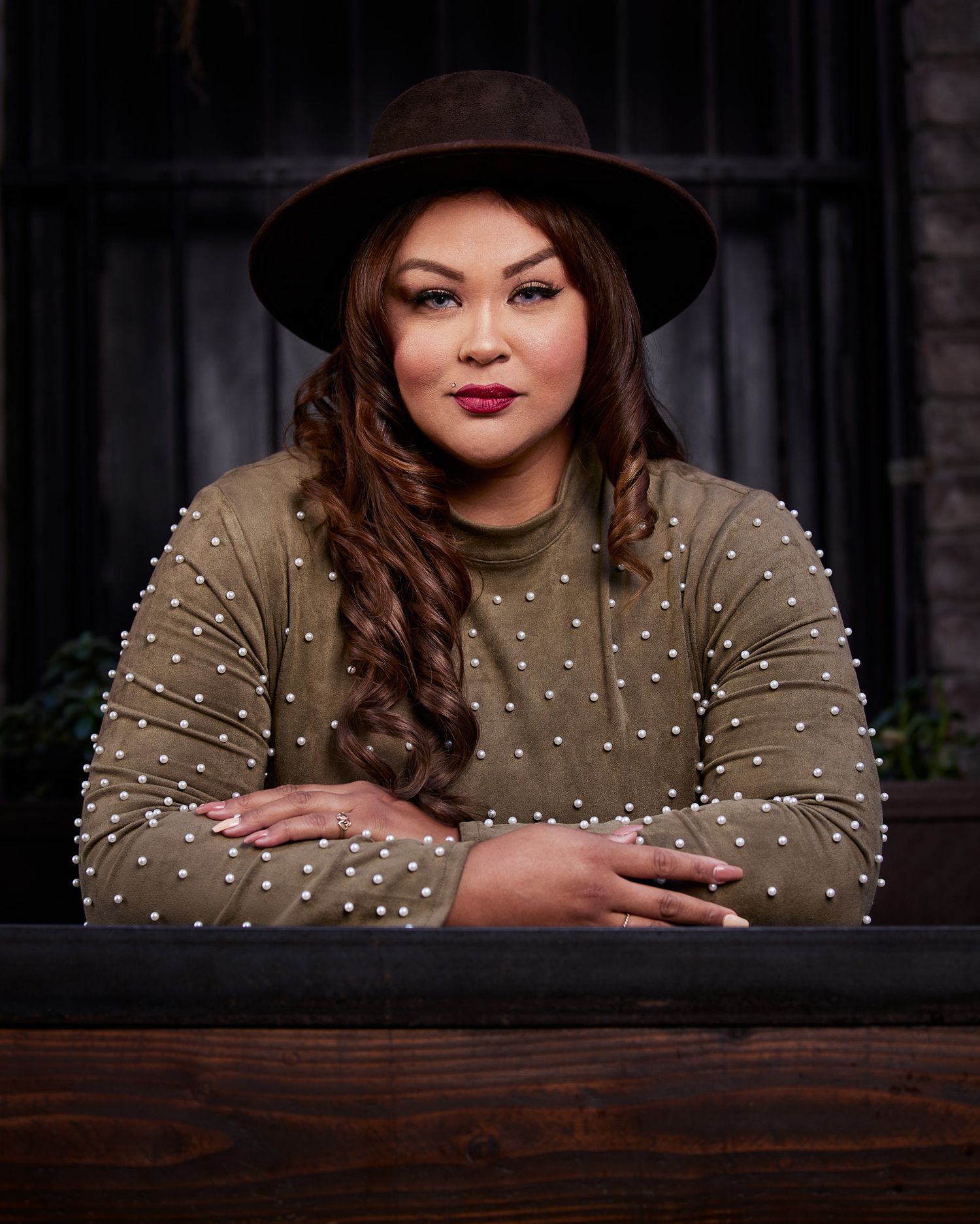 Stylish portrait featuring brown hat and pearl-embellished sweater.