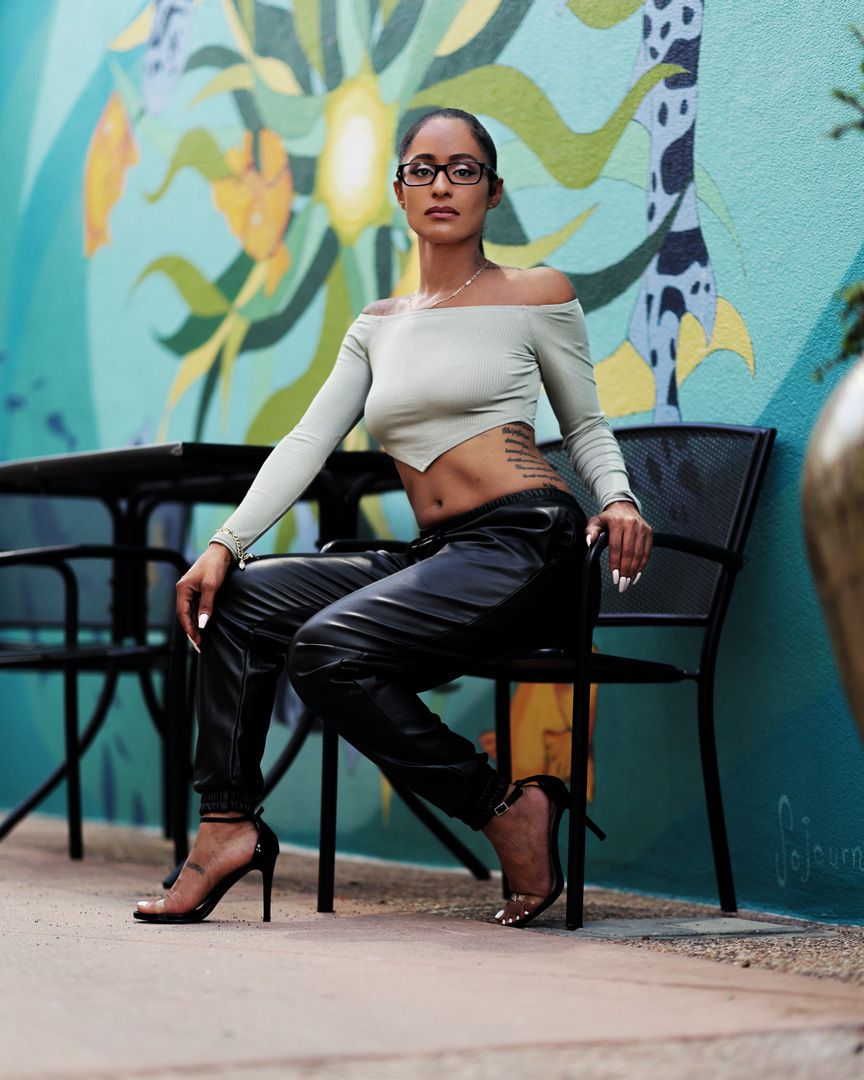 Modern fashion pose in off-shoulder crop top against colorful mural wall.