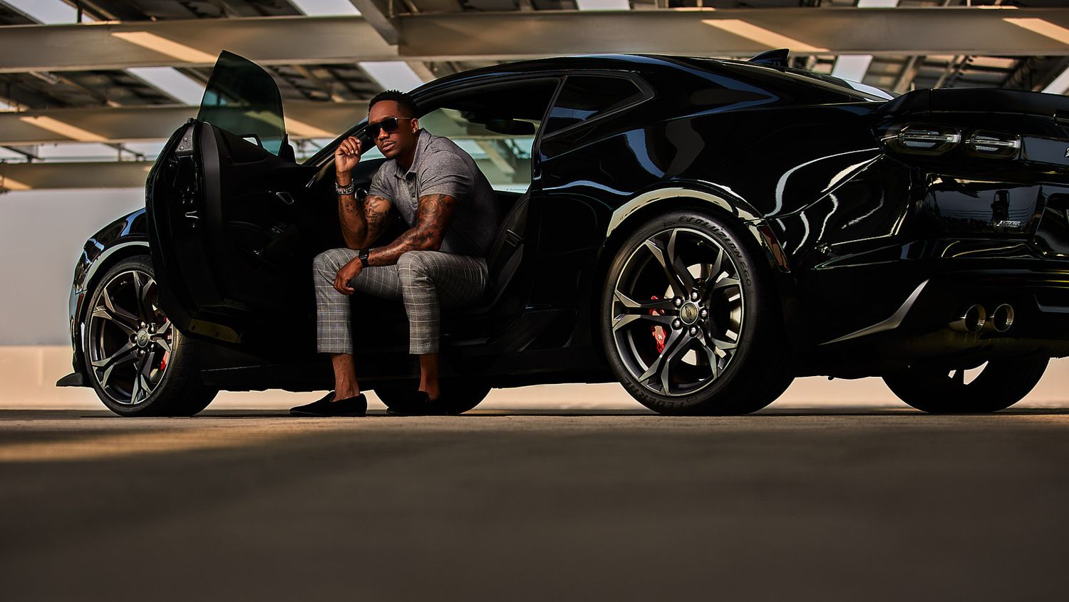 Silhouette of person sitting in luxury sports car in dark parking garage.