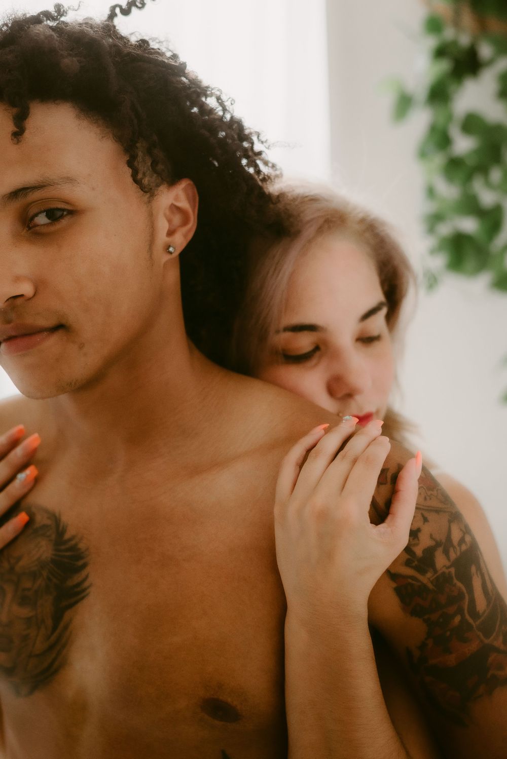 Close-up intimate portrait showing tattoo details and gentle expressions.
