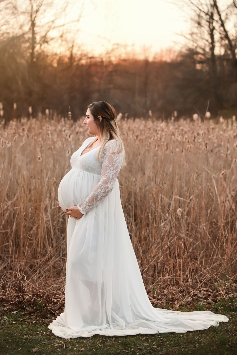 Fine art outdoor maternity portrait in Winter with tall grass and long flowy dress