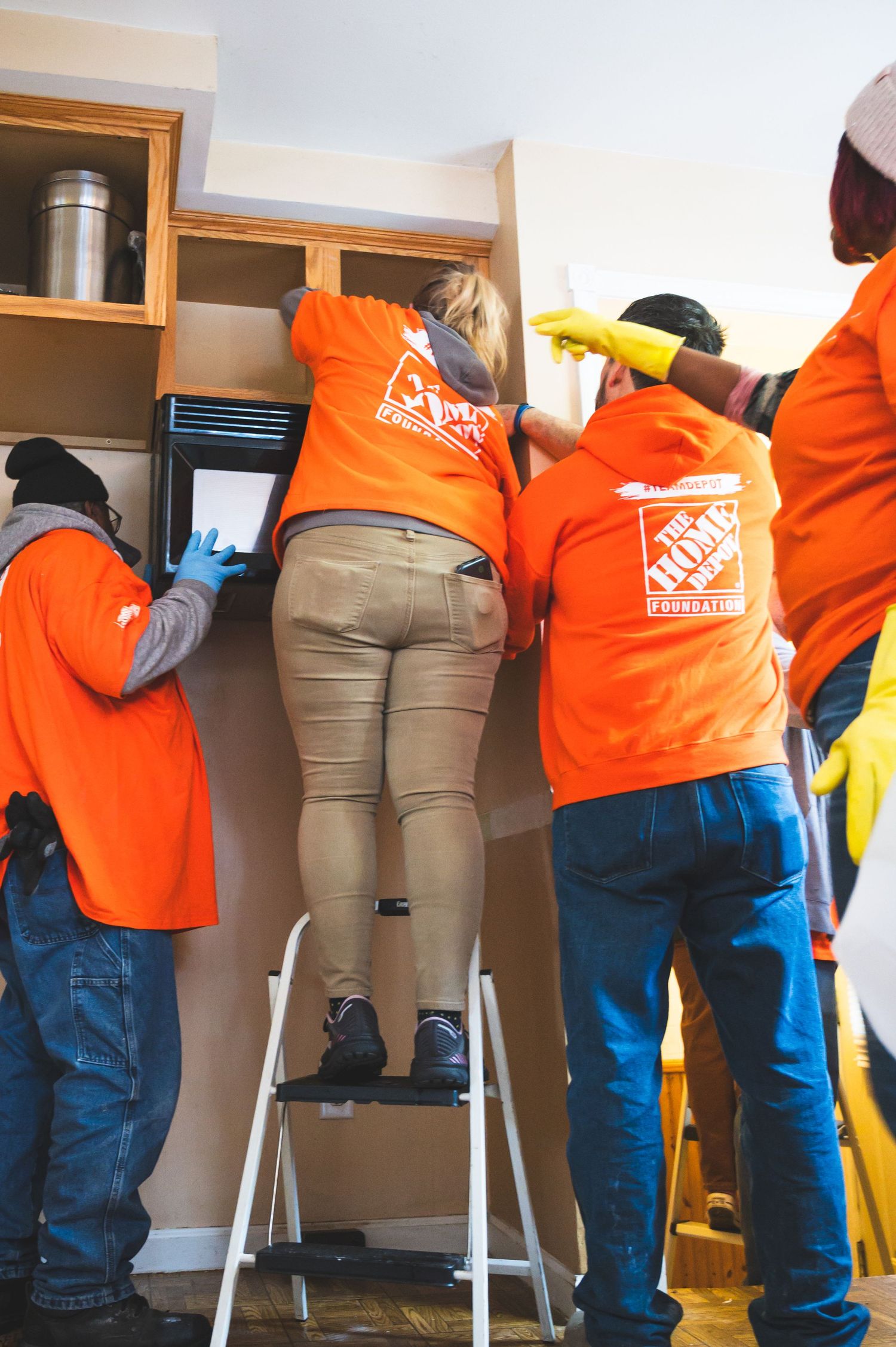 Home Depot volunteers working together to install kitchen cabinets.