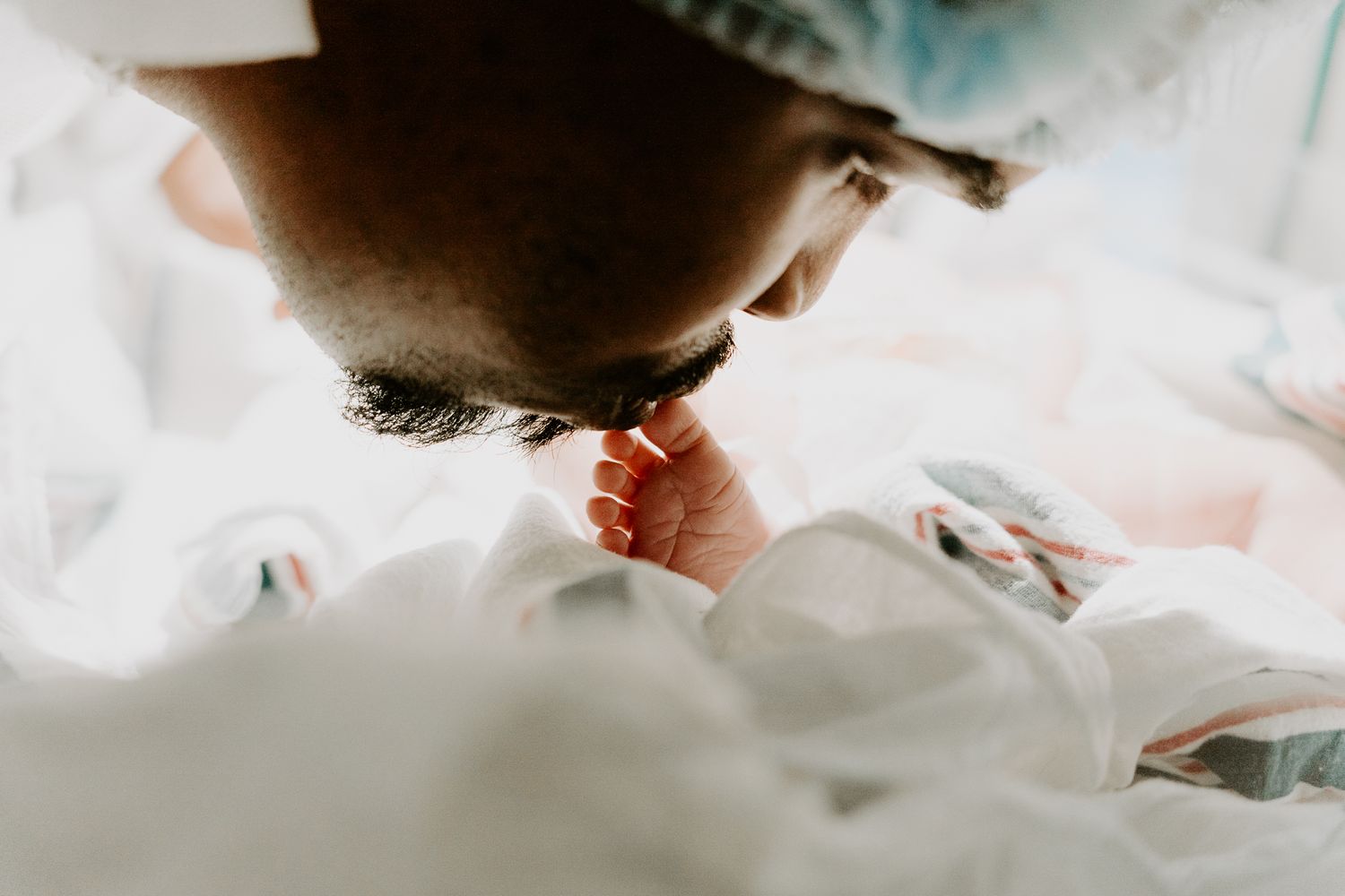 dad kissing baby foot. dallas kissing baby girl. proud father with new born baby girl dallas texas newborn photographer.