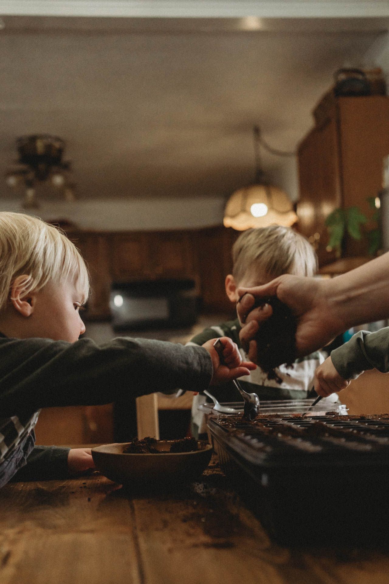 Kids helping in kitchen with baking activities in moody lighting.