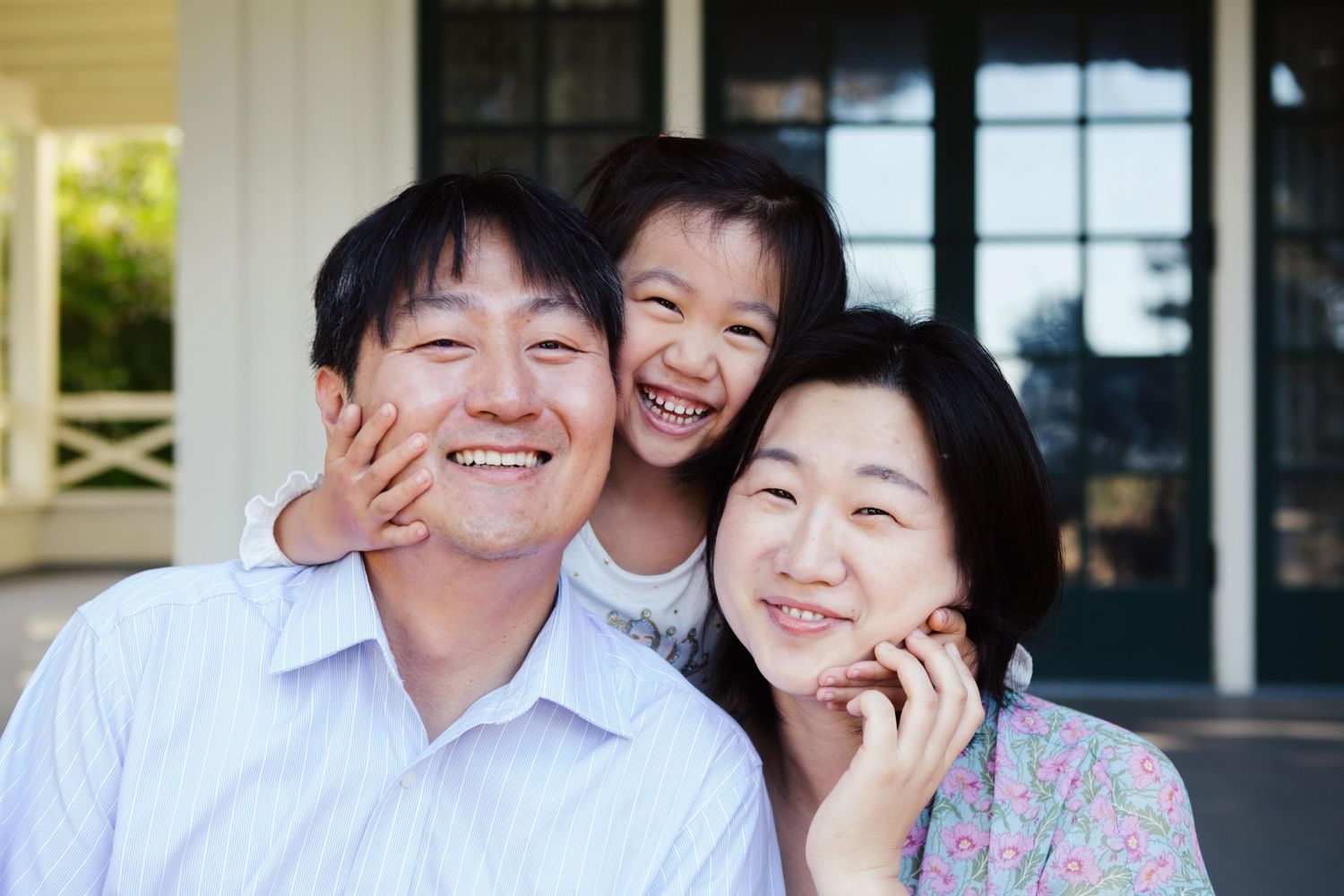 Family group portrait series on a porch showing natural expressions and laughter.
