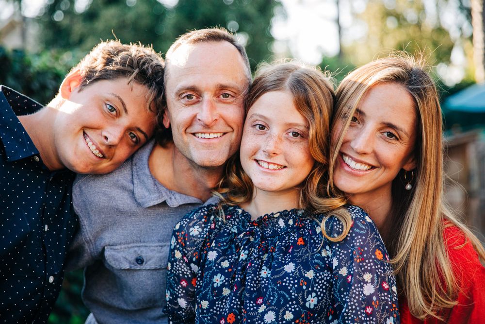 A close-up outdoor family portrait with matching navy and floral outfits.