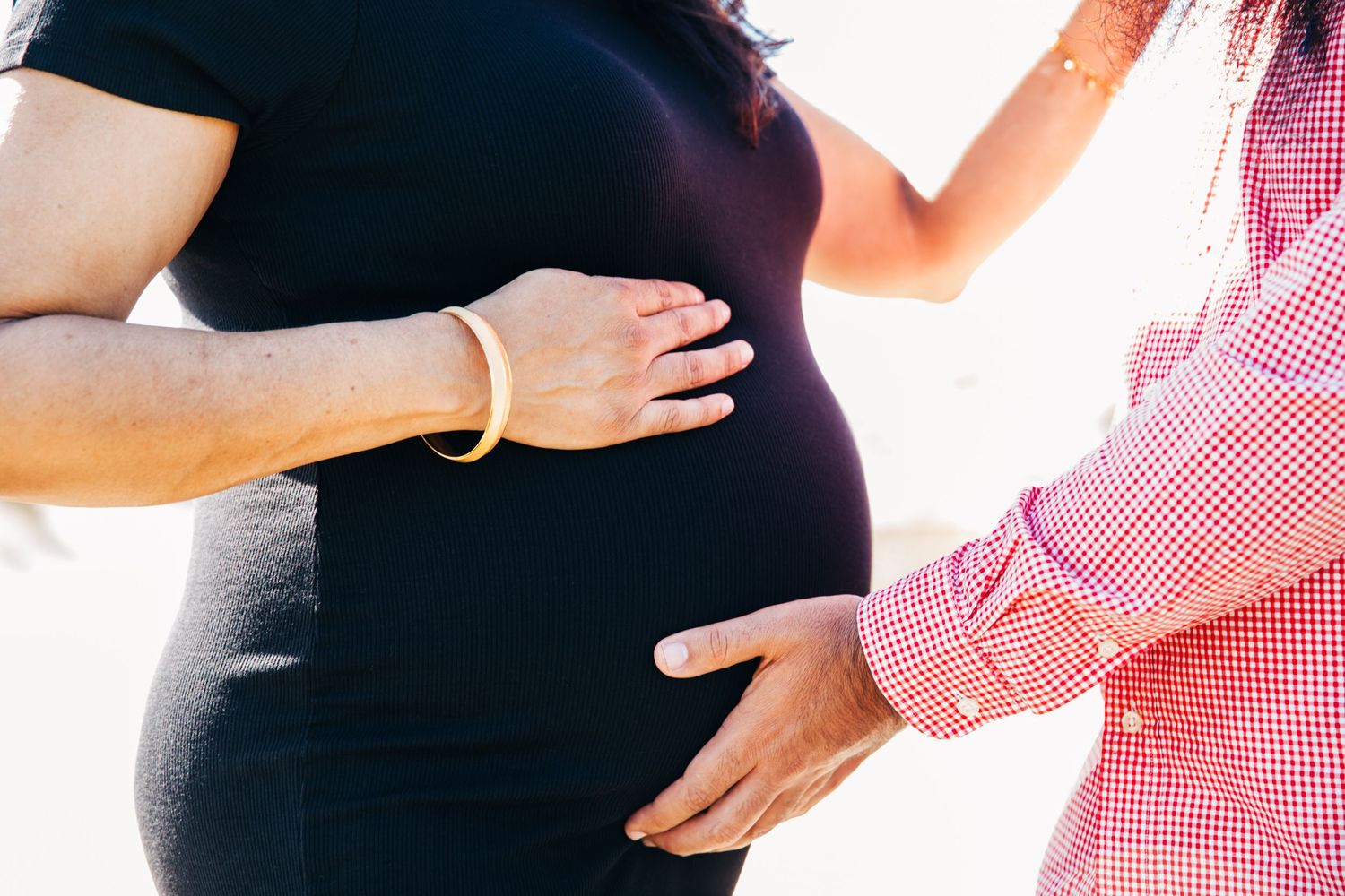 Hands gently rest on a pregnant belly in a tender maternity moment.
