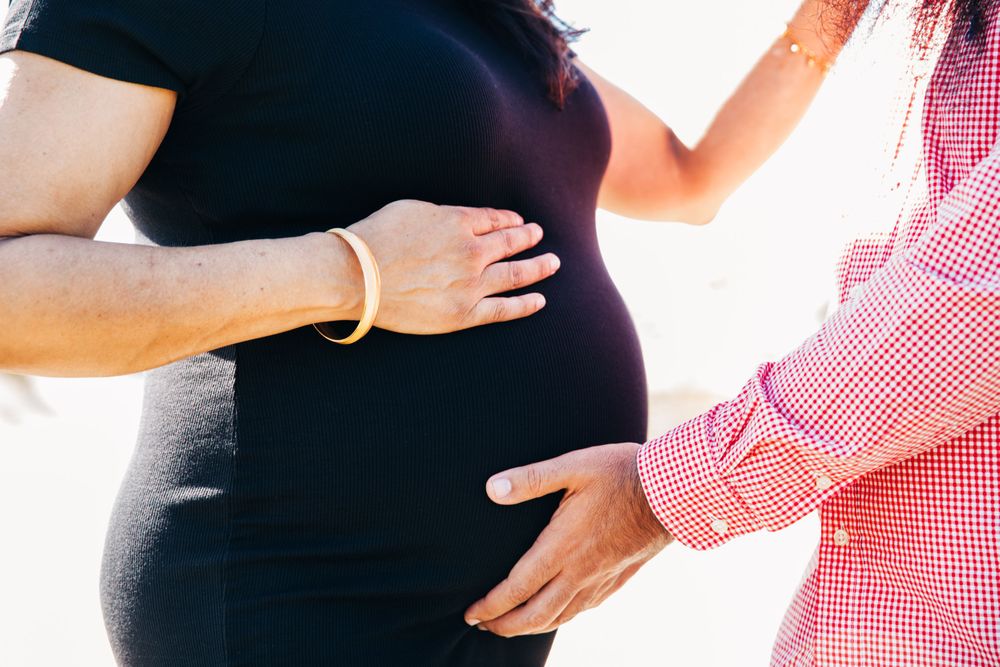 Hands gently rest on a pregnant belly in a tender maternity moment.