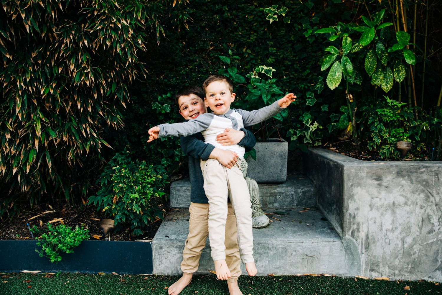 Family portrait session in a lush garden setting with stone walls.