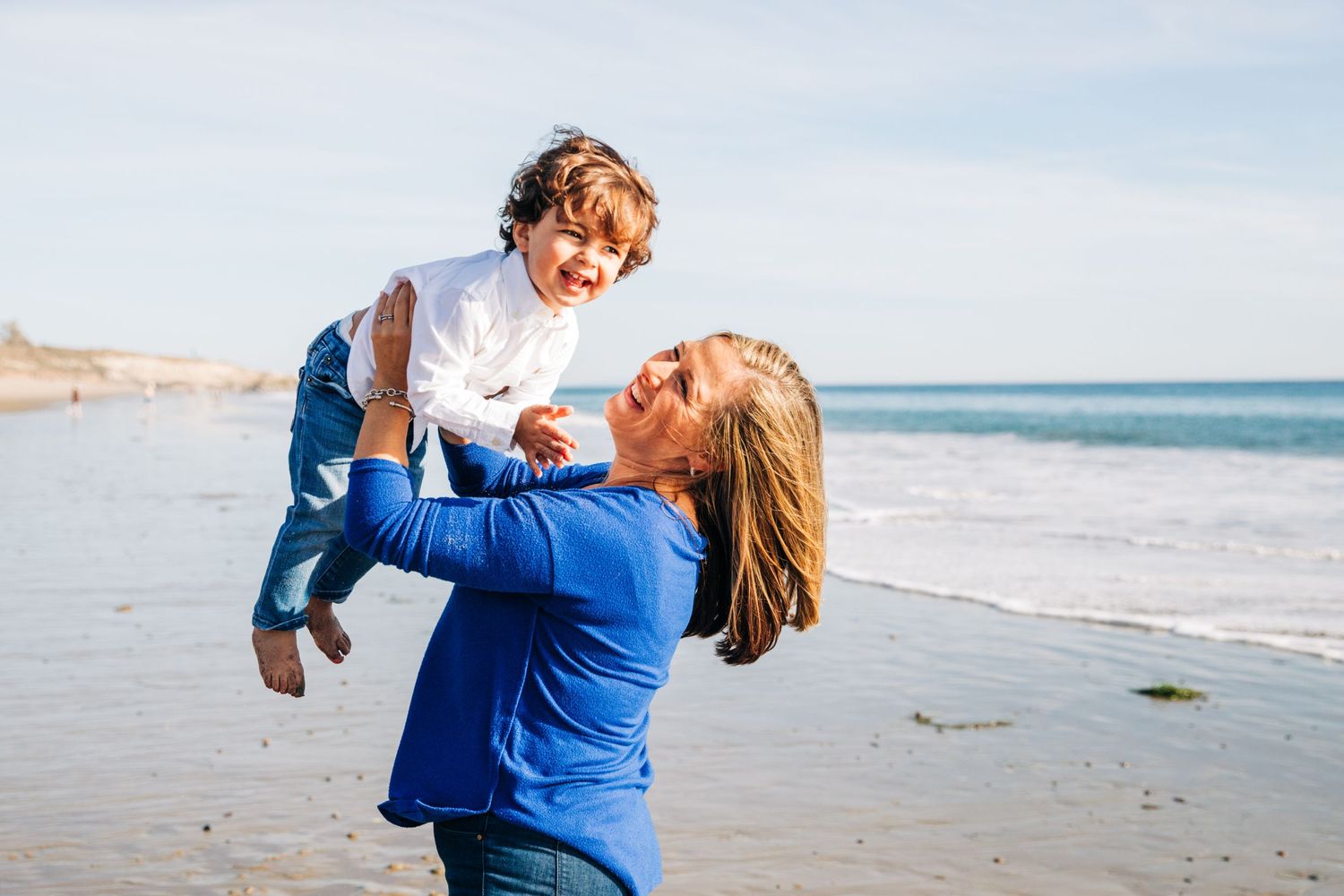 A joyful moment captured on the beach with people embracing and laughing together.