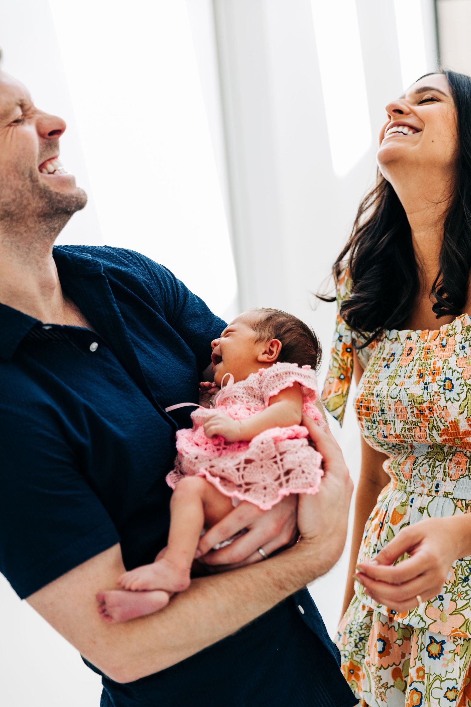 A joyful moment shared with a newborn baby wearing pink lace.