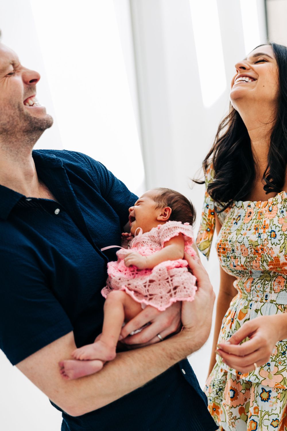 A joyful moment shared with a newborn baby wearing pink lace.