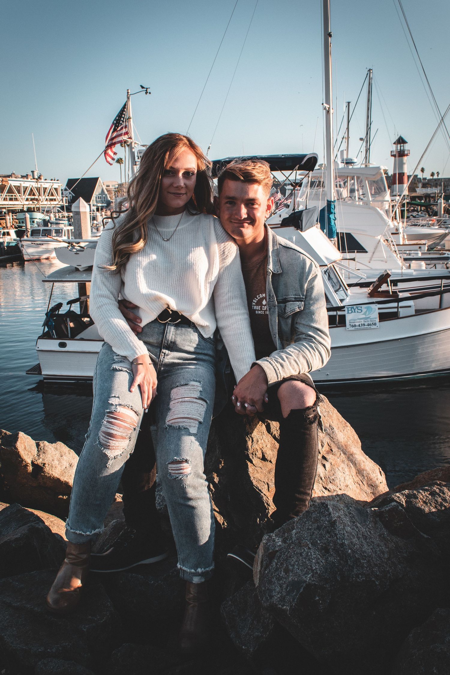 Couple posing on rocks at oceanside harbor in oceanside, ca