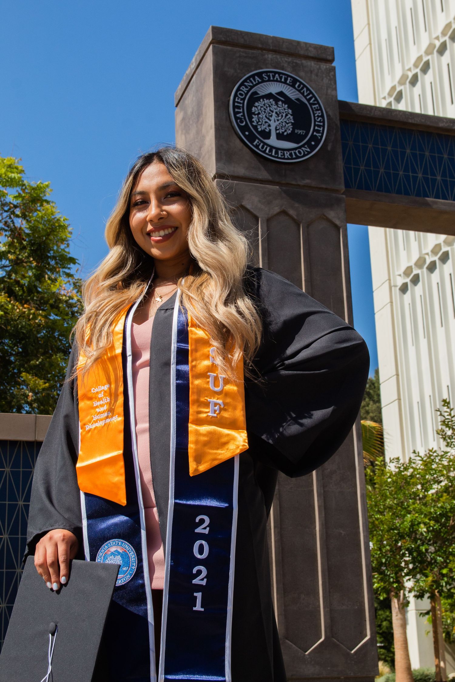 graduating woman posing in from of emblem at UC fullerton in fullerton, ca