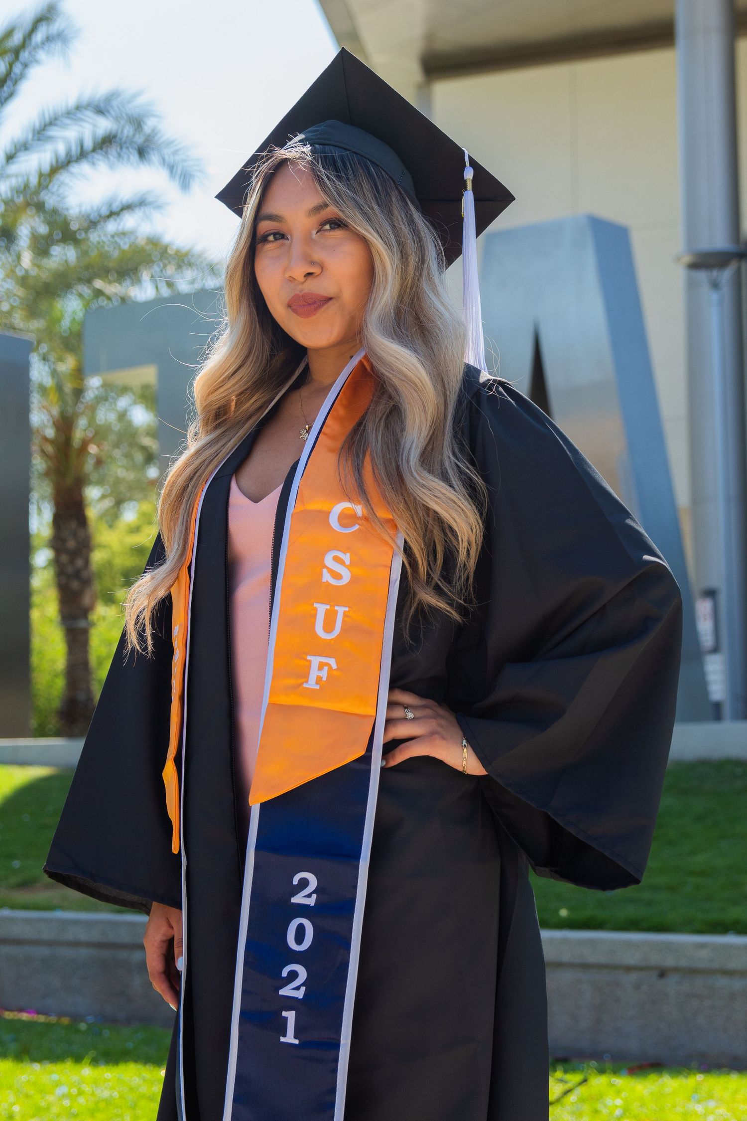 graduating woman posing in front of school sign at UC fullerton in fullerton, ca