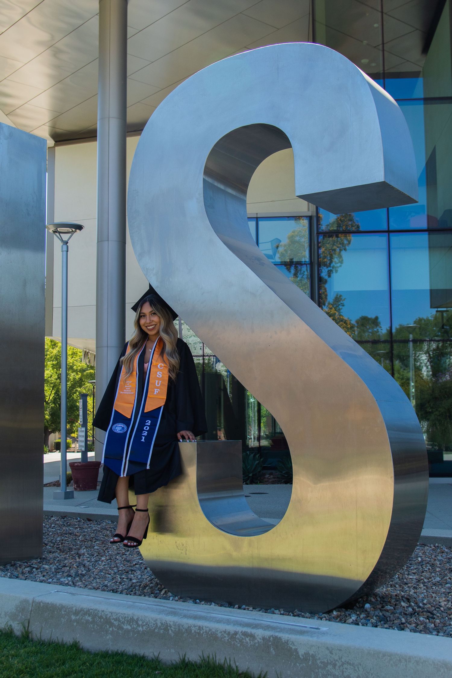 graduating woman posing in front of school sign at UC fullerton in fullerton, ca