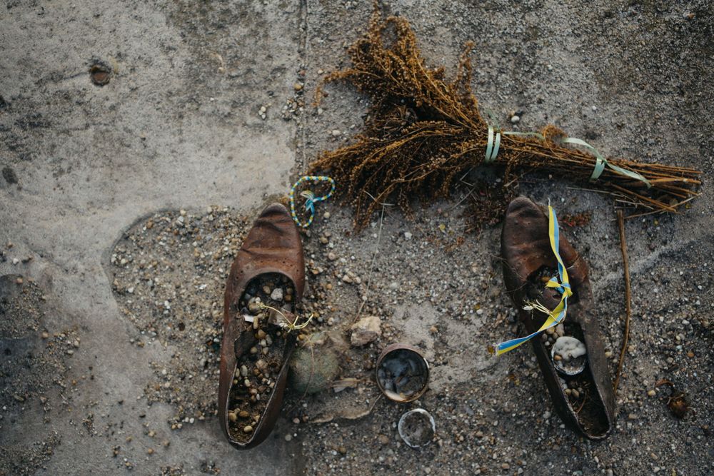 Collection of discarded shoes and debris on concrete ground.
