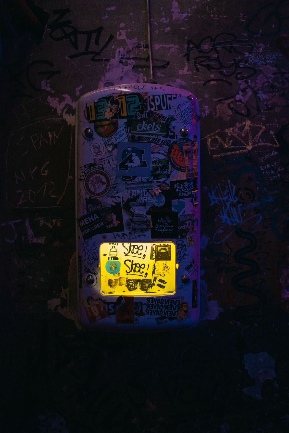 Graffiti wall illuminated by yellow light in dark underground passage.