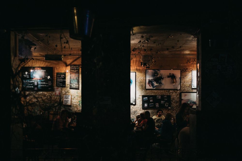 Dark industrial space with distant lights creating silhouettes through doorways.