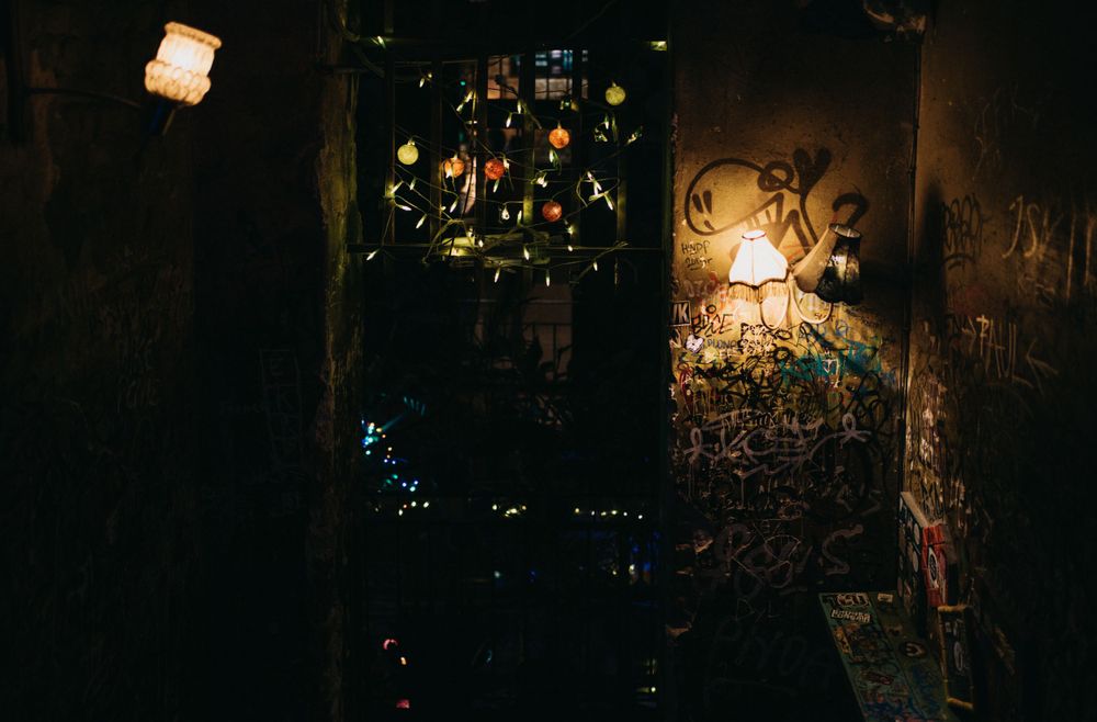 Nighttime urban scene with scattered lights illuminating graffiti walls.