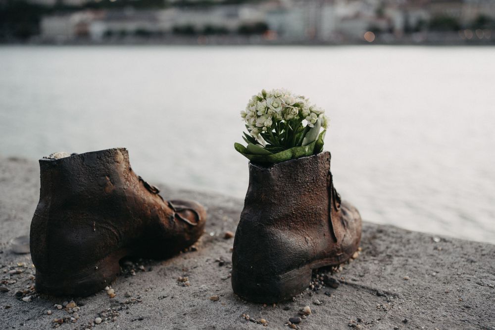 Weathered leather boots arranged artistically on a gray stone surface.