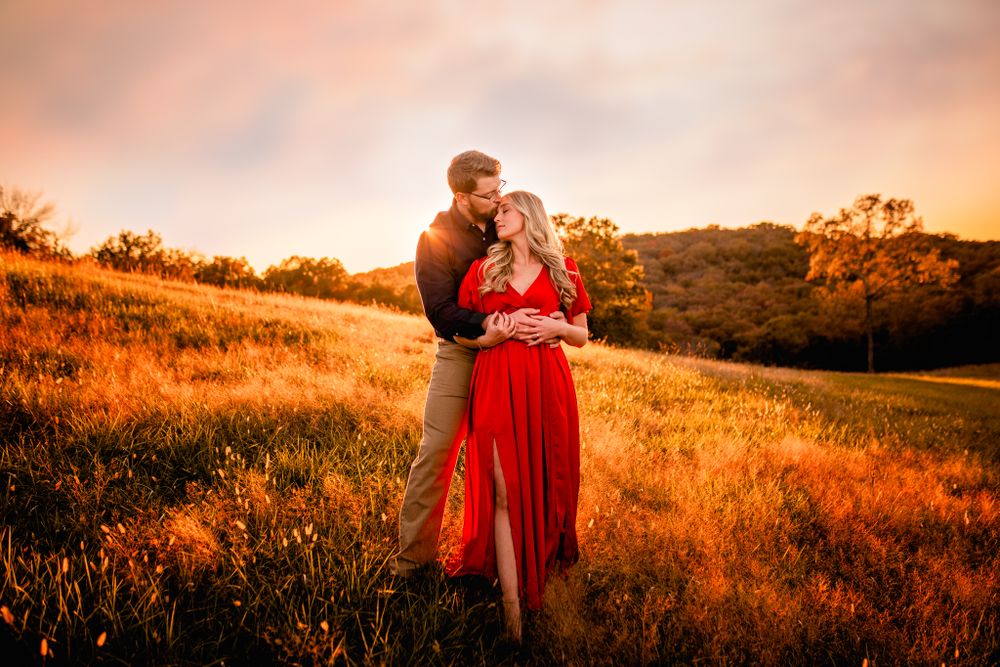 Engaged couple embracing in a golden field at sunset in Branson, MO, captured during a romantic golden hour baltic born