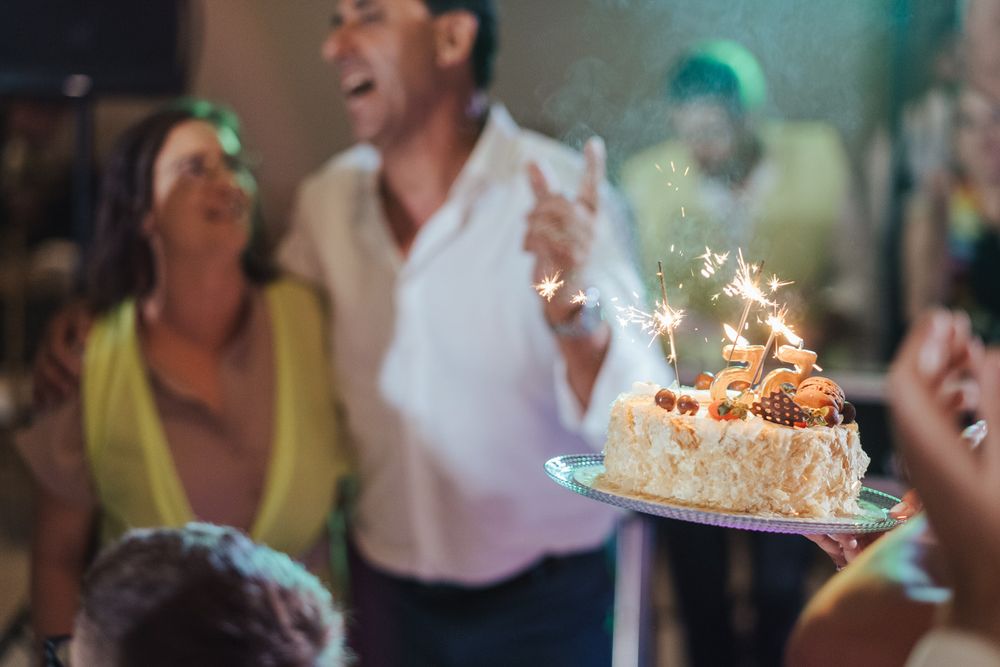Um bolo de aniversário com velas de faísca acesas brilha intensamente durante a celebração noturna.