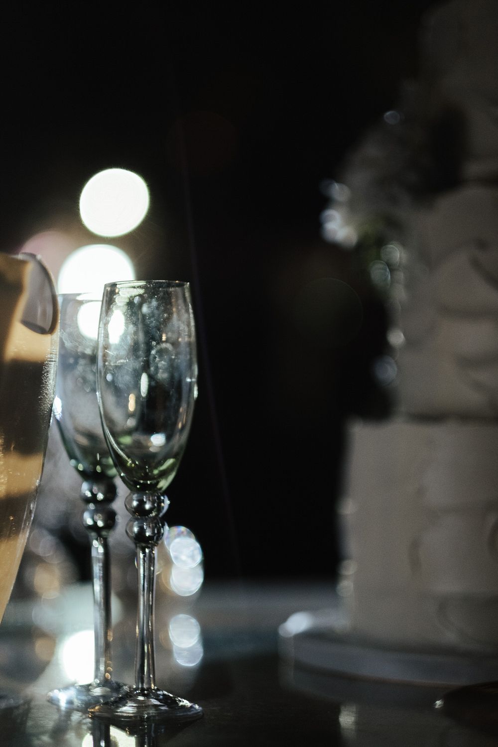 Copos de vinho vazios dispostos sobre uma mesa escura com suaves efeitos de iluminação bokeh.