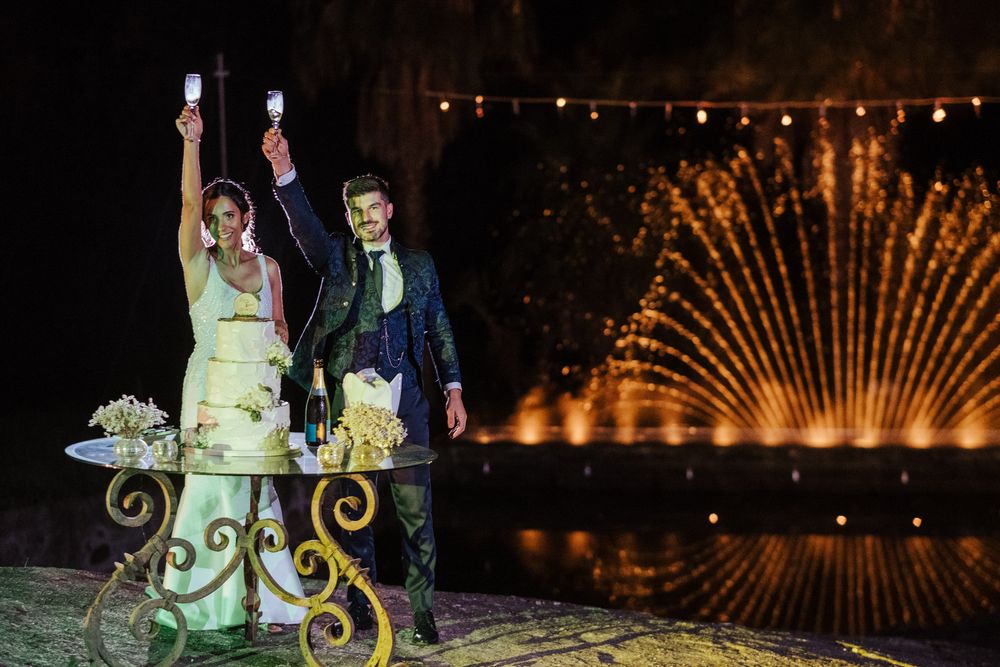 Celebração de casamento à noite com fontes iluminadas criando um cenário deslumbrante.