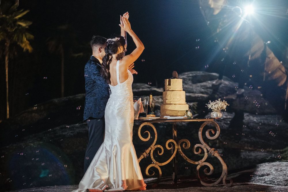 Cerimónia de corte do bolo de casamento iluminada por holofotes brilhantes à noite.