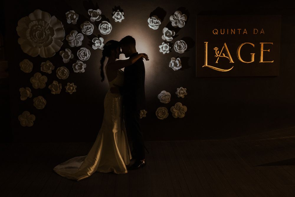 As decorações de flores de papel branco adornam uma parede escura com uma iluminação elegante num local de eventos.