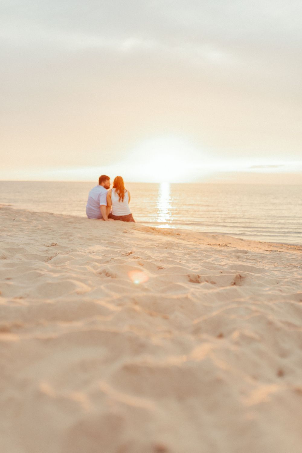 A couple sitting on the beach watching a beautiful ocean sunset together.