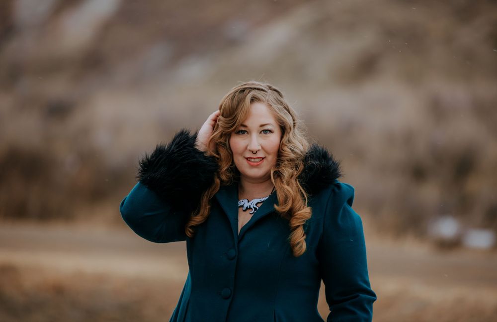 A cheerful winter fashion portrait featuring a navy coat with black fur trim.
