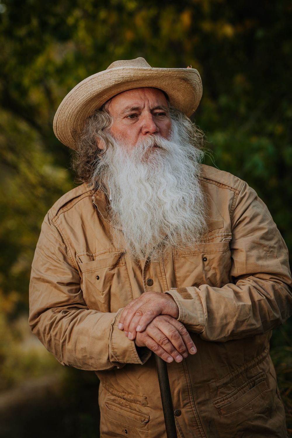 A rustic portrait showing weathered workwear and a straw hat against natural foliage.