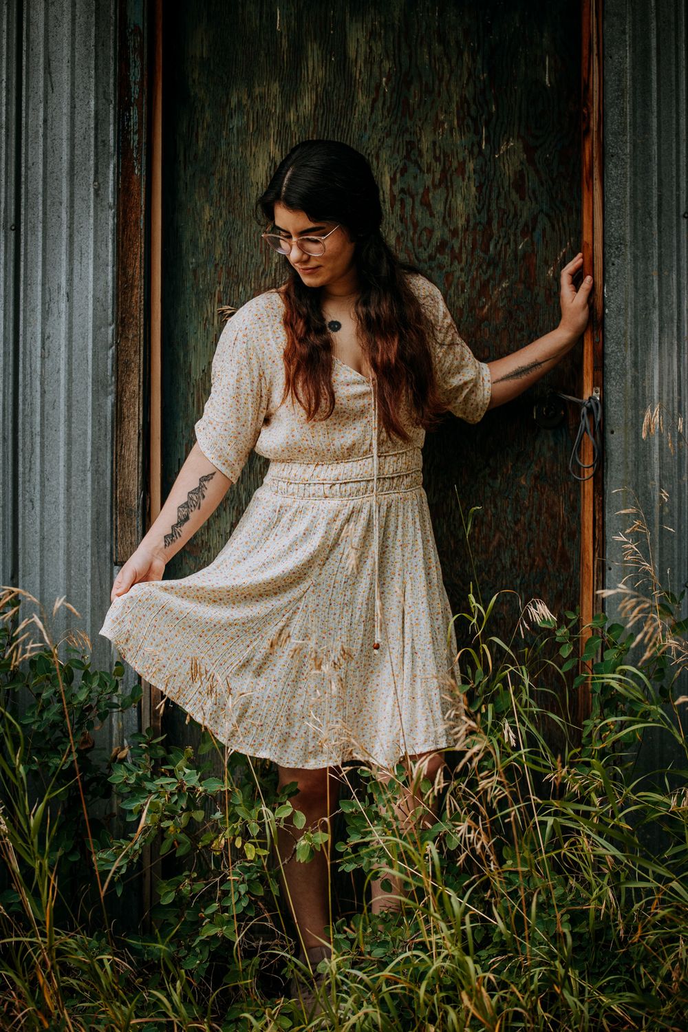 A dreamy portrait in a vintage cream lace dress standing against weathered wood and wild grasses.