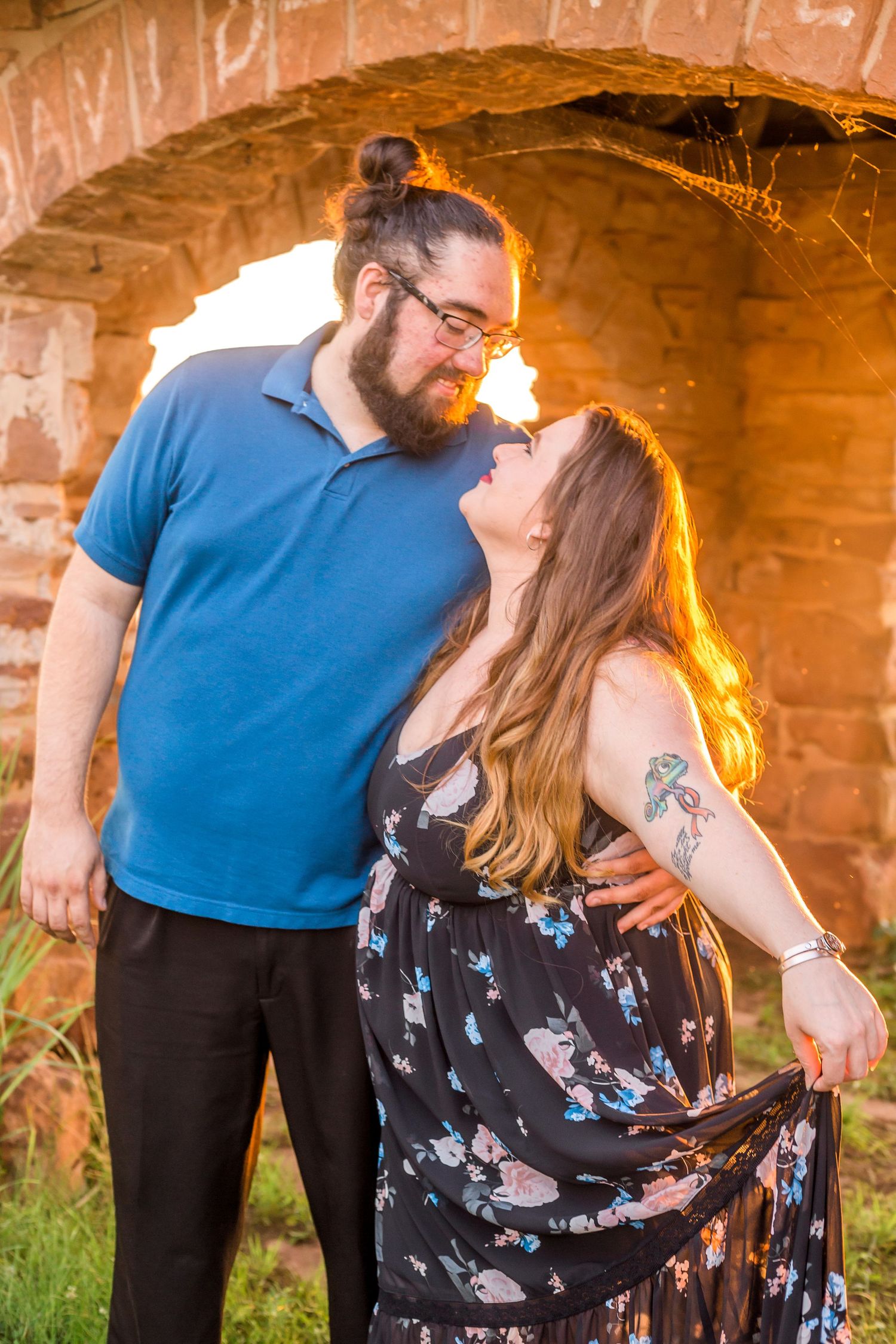 Romantic sunset portrait under a brick archway with golden lighting.