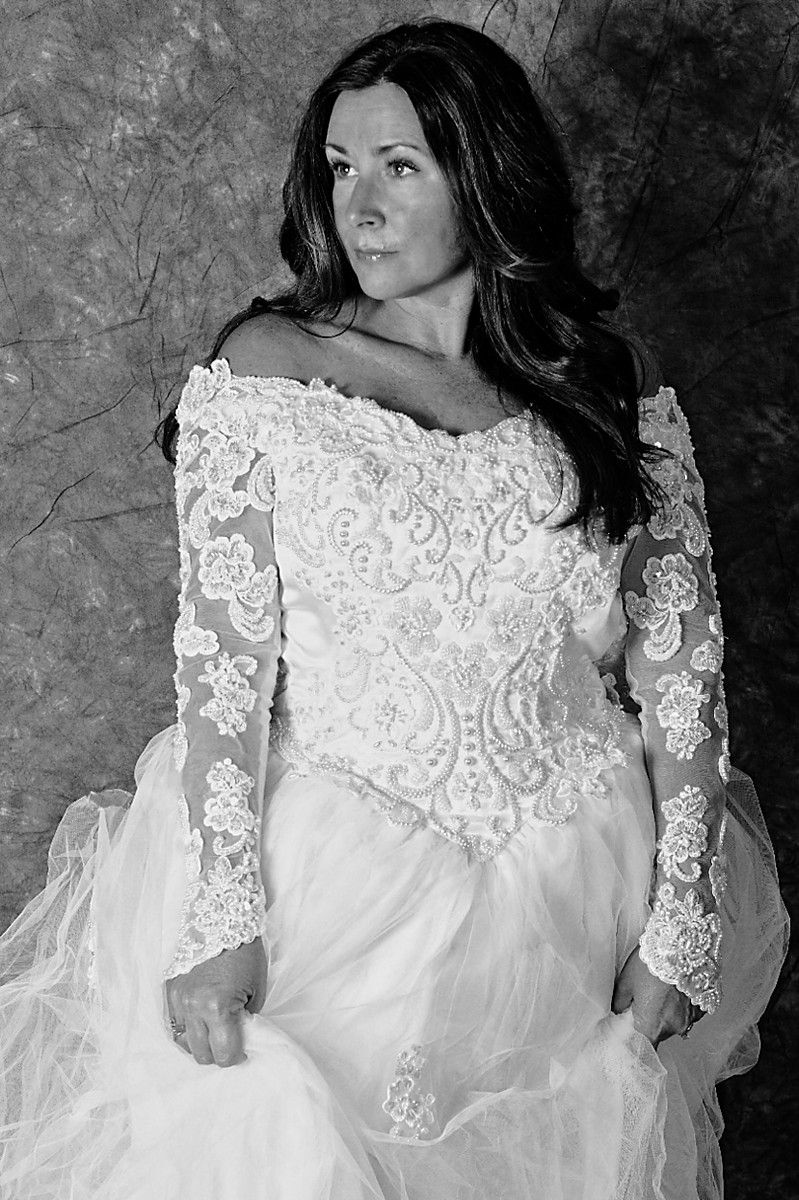 Black and white portrait of woman in elegant white lace wedding gown.