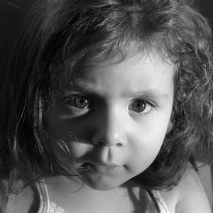 Black and white close-up portrait showing dramatic lighting on a young child's face.