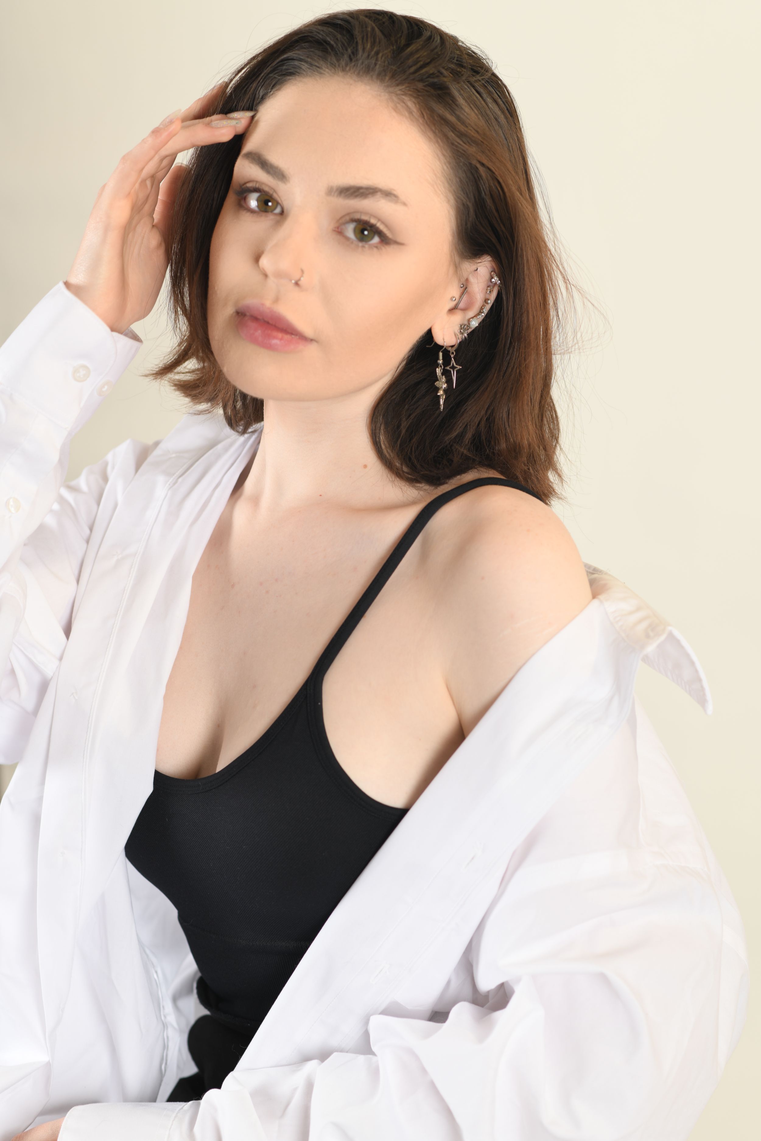 Fashion portrait of model in black tank top and white shirt against light background.