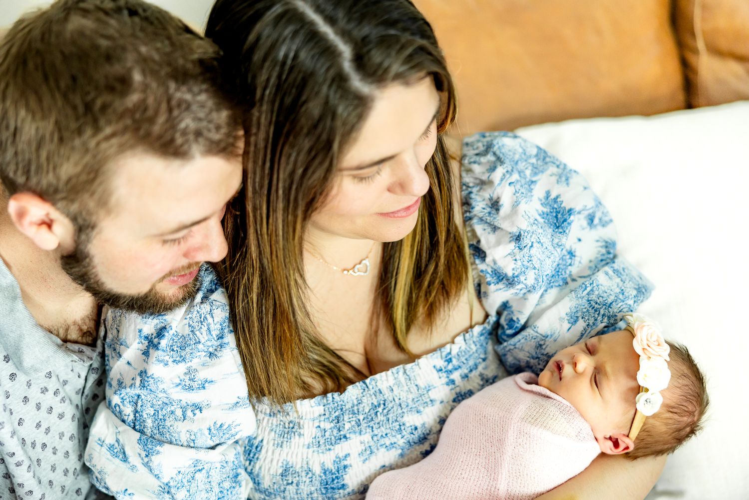 Mom holds new baby girl as she and dad gaze at her during lifestyle newborn photos in Colorado Springs.